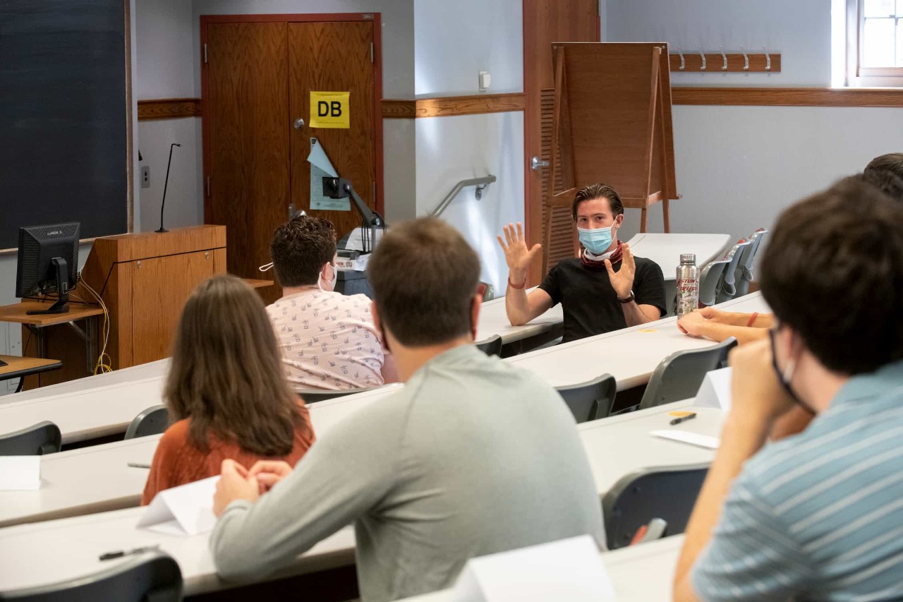 masked students talk animatedly in a classroom