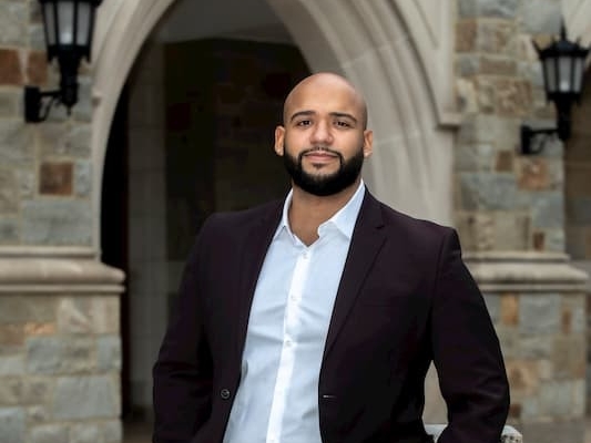 Dewin Hernandez standing by Fulton Hall. 