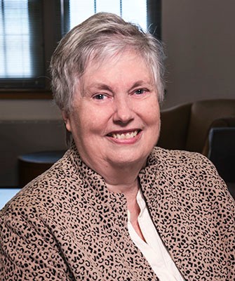 Headshot of woman with short white hair in a printed blazer.