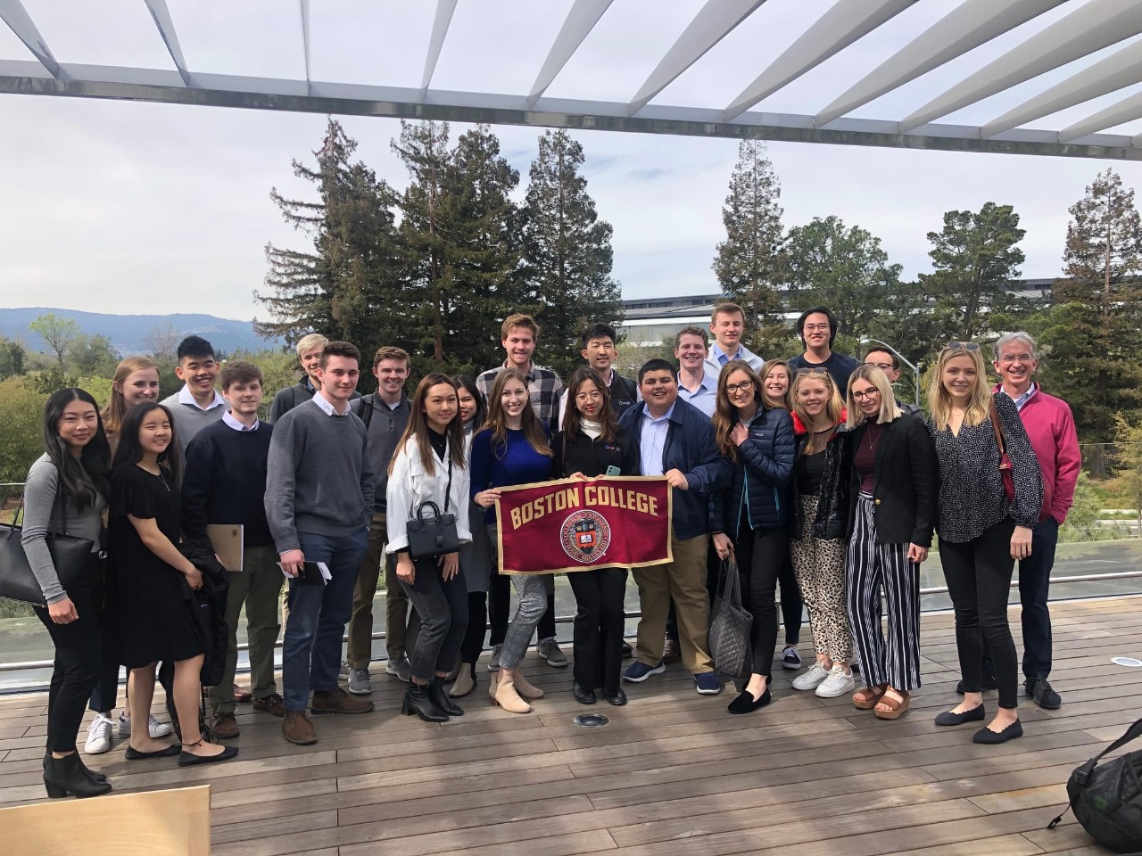 group photo of students holding boston college banner on a patio