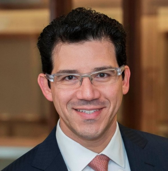 Headshot of Ronnie Sadka, a smiling white man in a suit