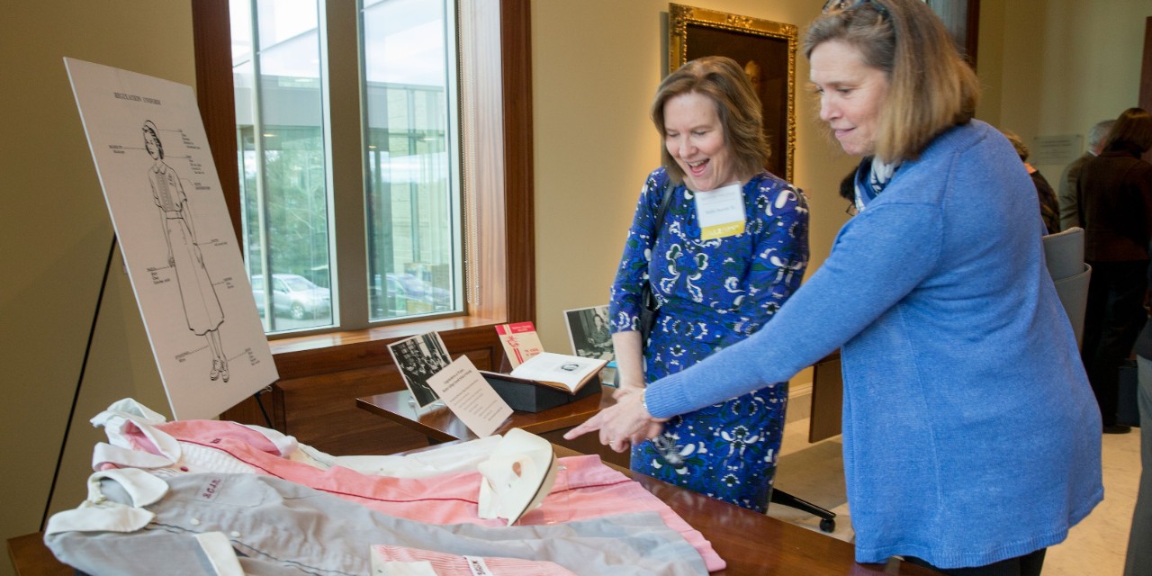 Kathy Barrett '81 and Elizabeth Fee '81 looking at exhibition of nursing objects from University archives