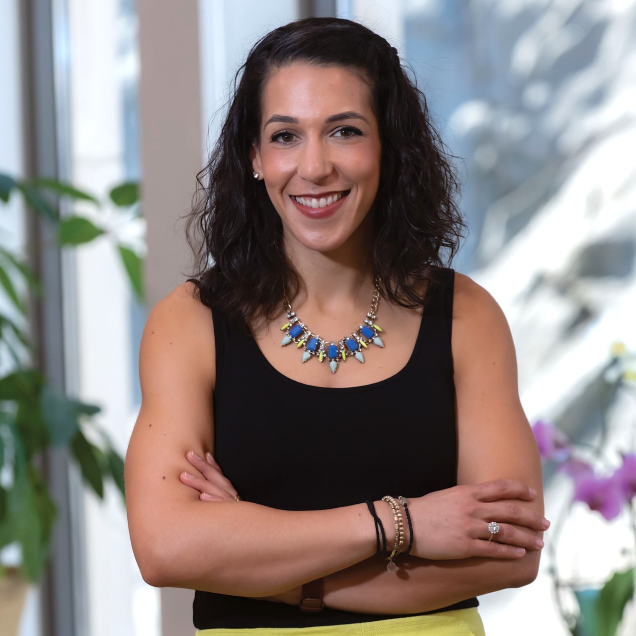 Nadia Abuelezam in black tank top with blue and green necklace