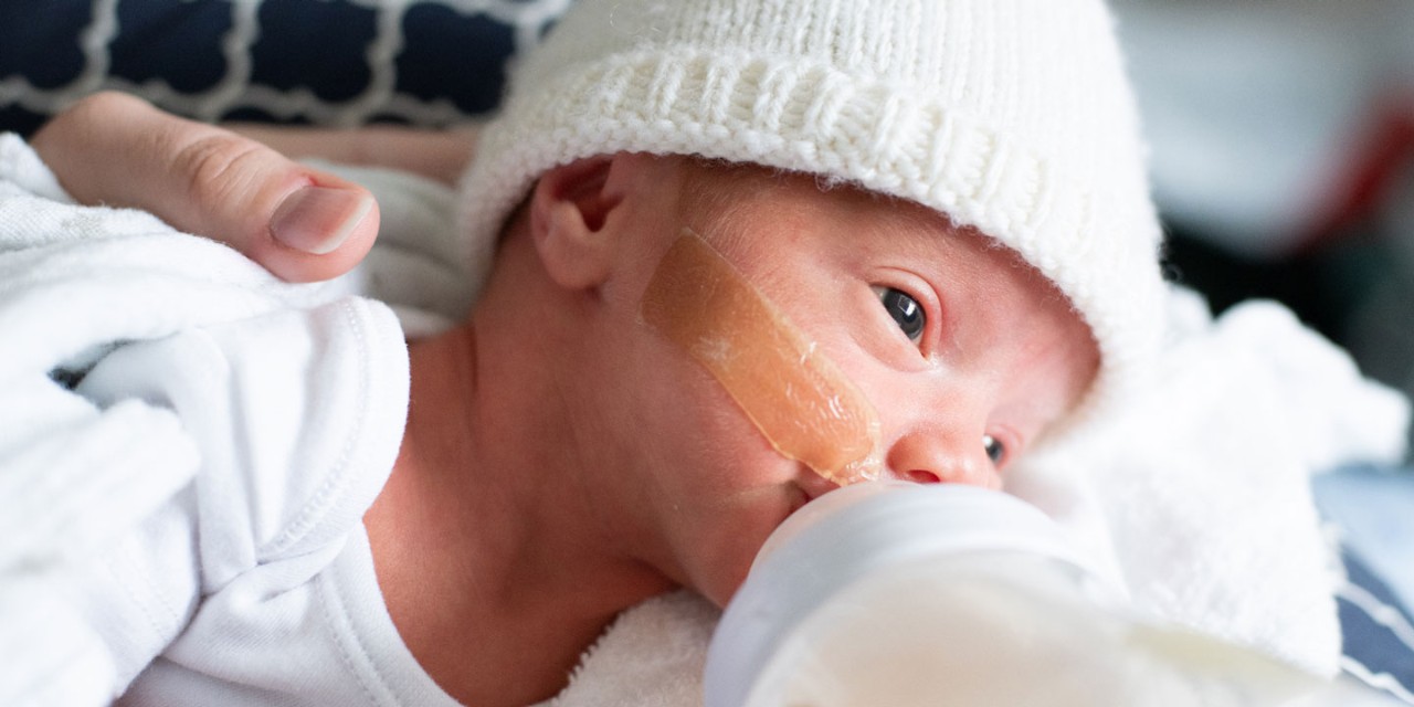 Baby feeding in white hat and white onesie