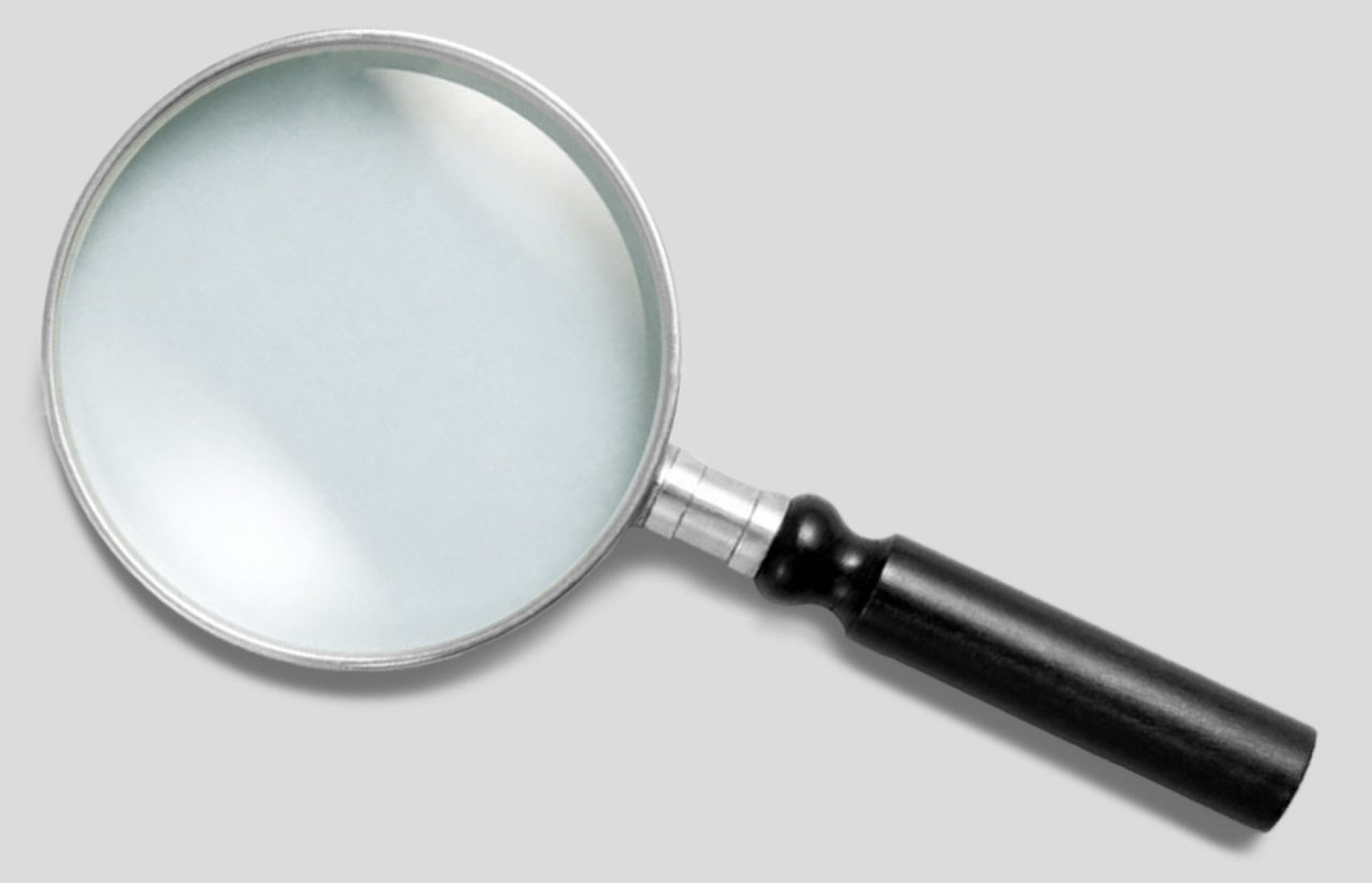 A magnifying glass lays on a solid gray background