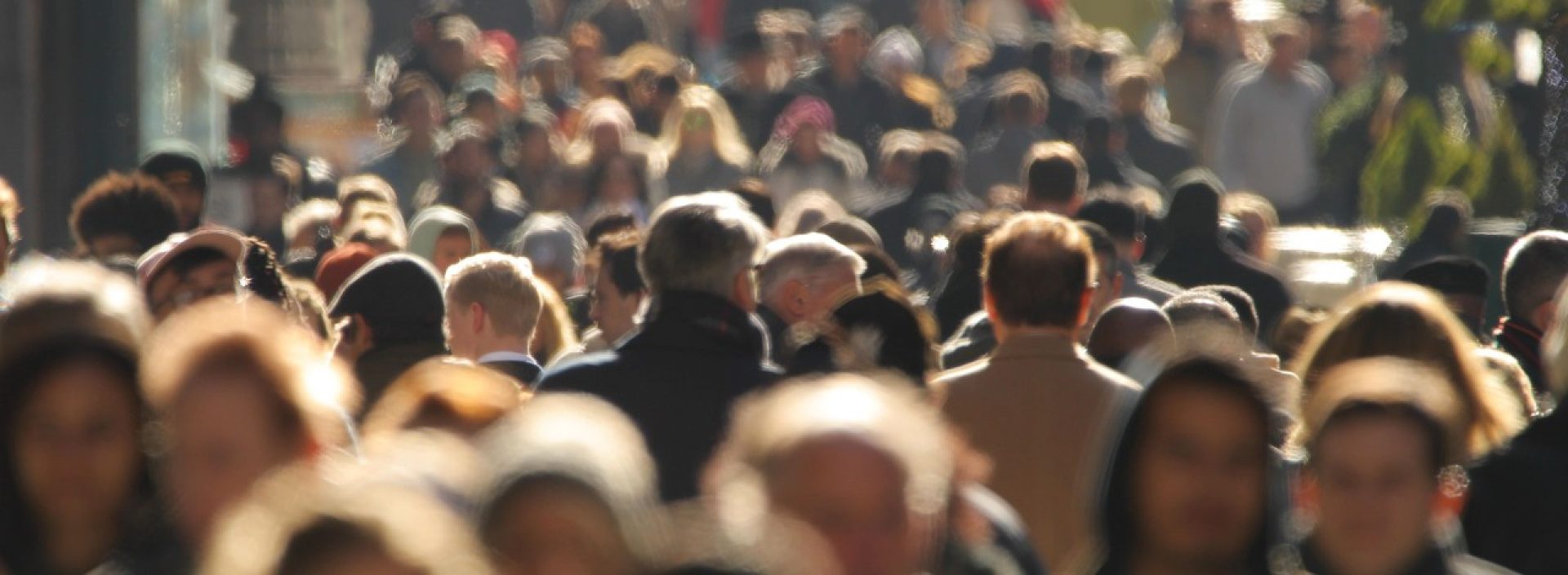 Crowd of people walking busy New York City street backlit