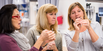 Nursing students interact one-on-one with instructor.