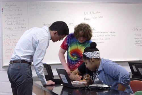 Students and their teacher looking at computers