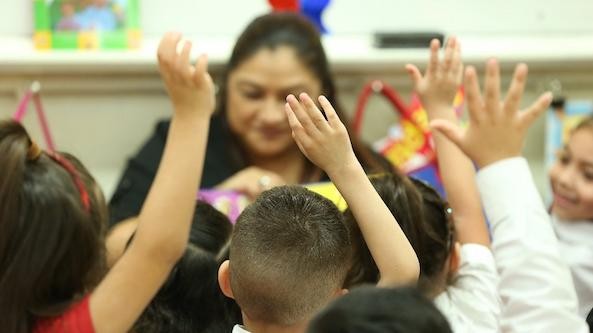 Teacher speaking to group of student with raised hand