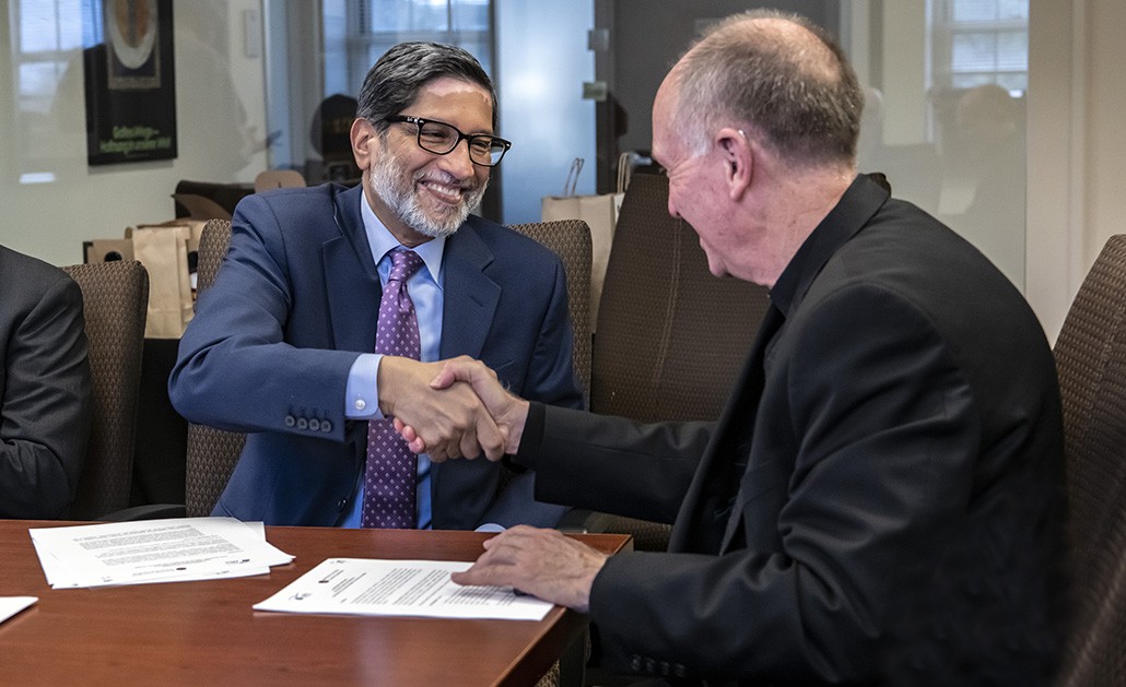 Gautam N. Yadama and Thomas H. Smolich, S.J., shake hands after signing the MOU. (Lee Pelligrini)