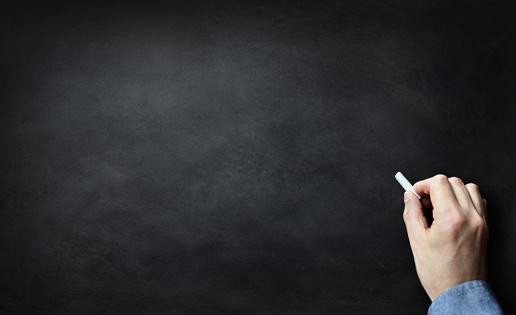 A photo of a hand writing on a chalkboard