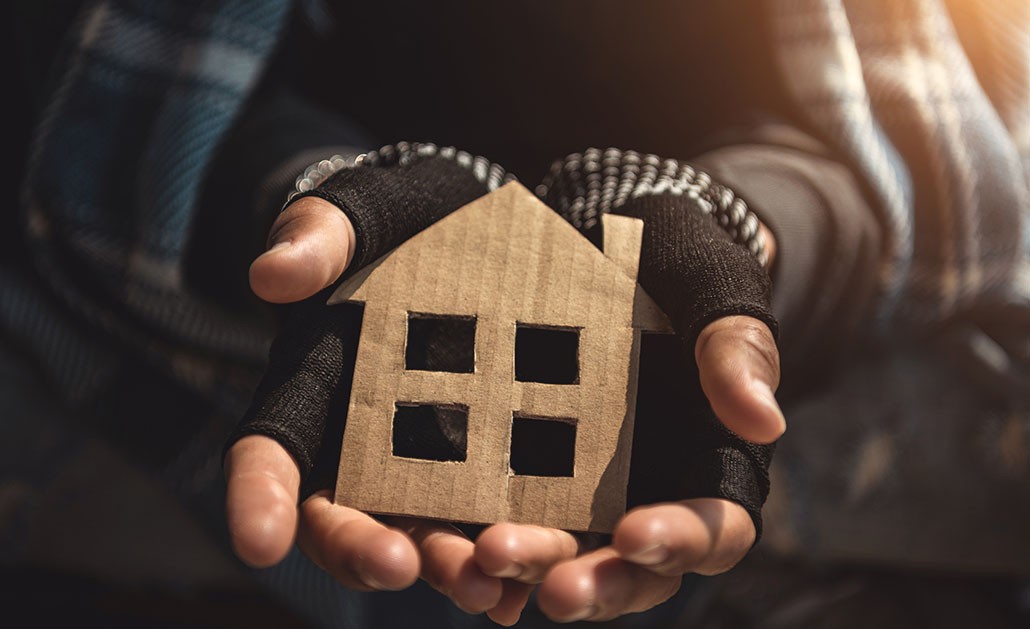 A photo of a person holding a house made of cardboard.