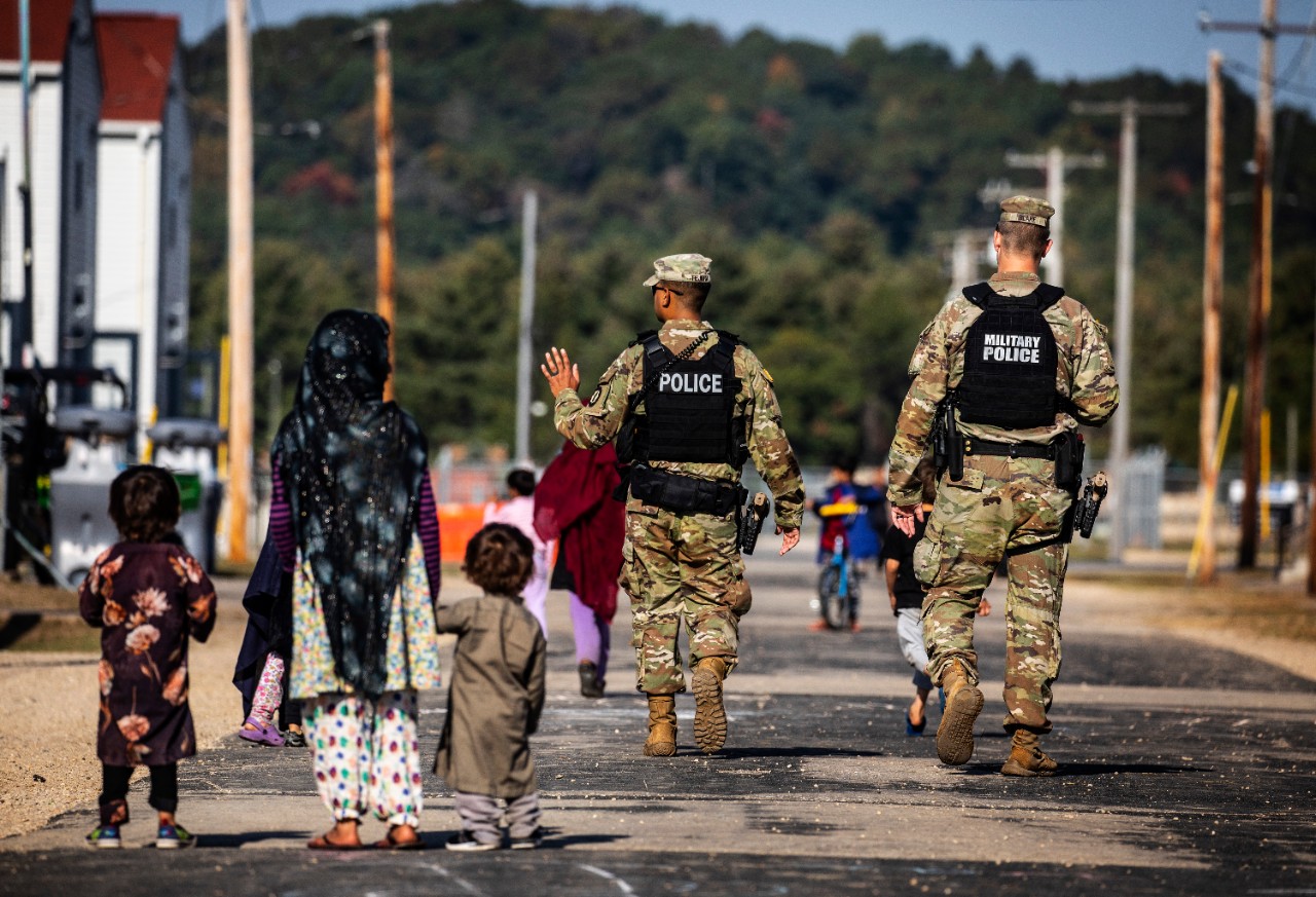 U.S. military police walk past Afghan refugees at the village at the Ft. McCoy Army base