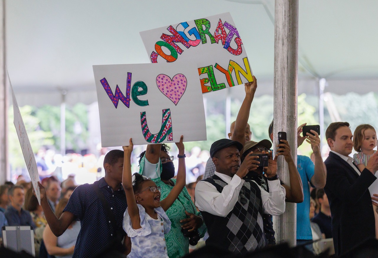 Guests hold up signs that say "We Love You" and "Congrats"