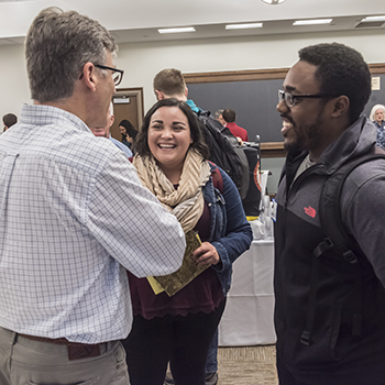 Participants and "recruiters" talking with each other at the STM Career Expo in Room 100 of Simboli Hall (9 Lake St.). Photographed for the Winter '18 issue of BCM. Dan Leahy of BC Campus Ministry talks with Dalia Gutierrez, a 2nd year MA student and John Gabelus, a 2nd year MA student.