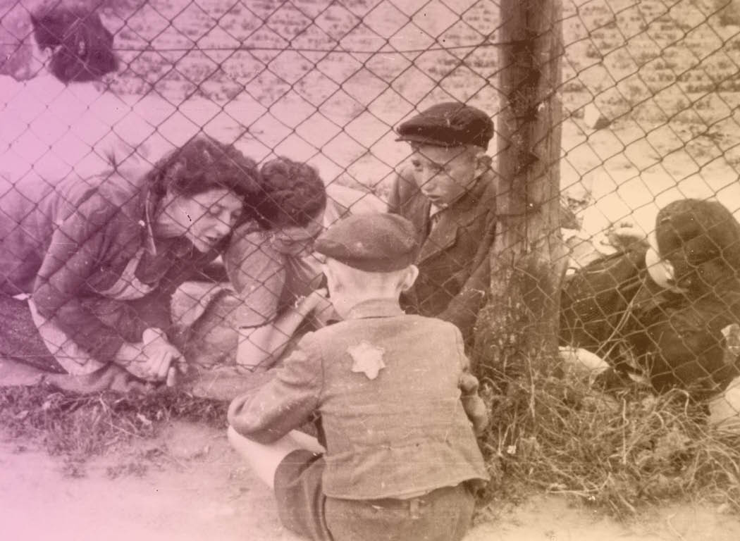 Lodz, Poland, Women and children on either side of a chain link fence in the ghetto. All rights reserved.  Used with permission of Yad Veshem.