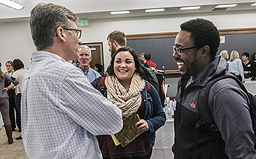 Participants and "recruiters" talking with each other at the STM Career Expo in Room 100 of Simboli Hall (9 Lake St.). Photographed for the Winter '18 issue of BCM. Dan Leahy of BC Campus Ministry talks with Dalia Gutierrez, a 2nd year MA student and John Gabelus, a 2nd year MA student.