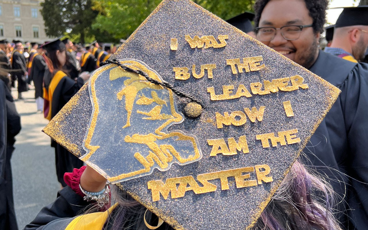 Woods student cap reading "I was but the learner now I am the Master"