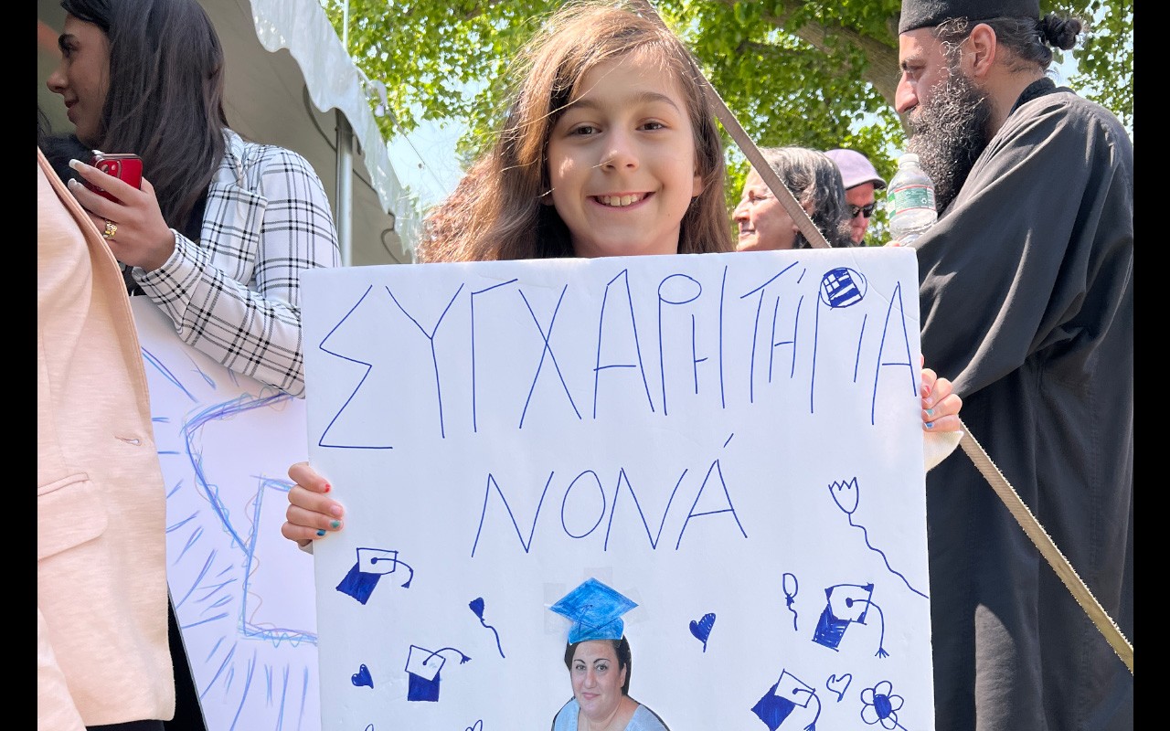 Litttle girl holding a sign congratulating a graduate