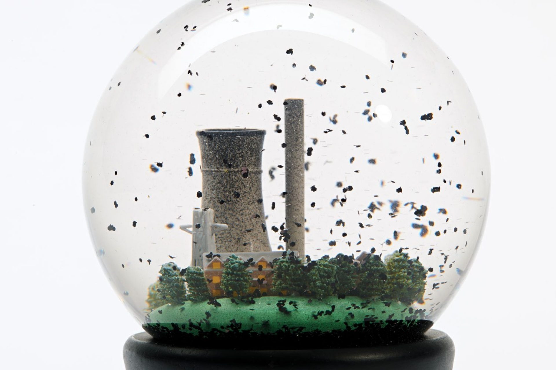 Snow globe with industrial landscape and dark flakes floating around
