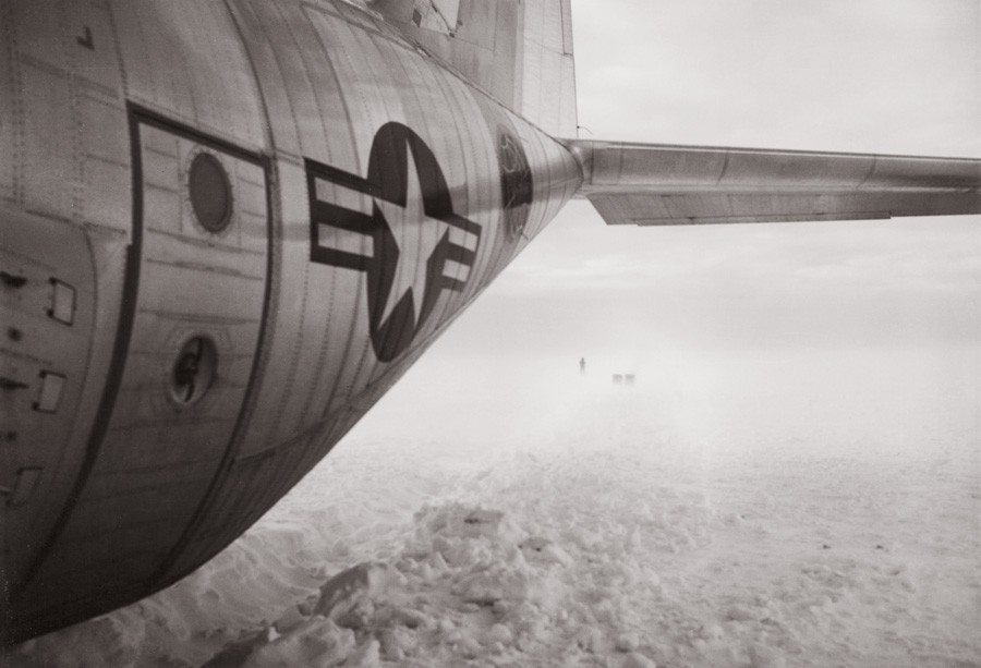 Fuselage of a C-130 Hercules with tiny figures in the distance