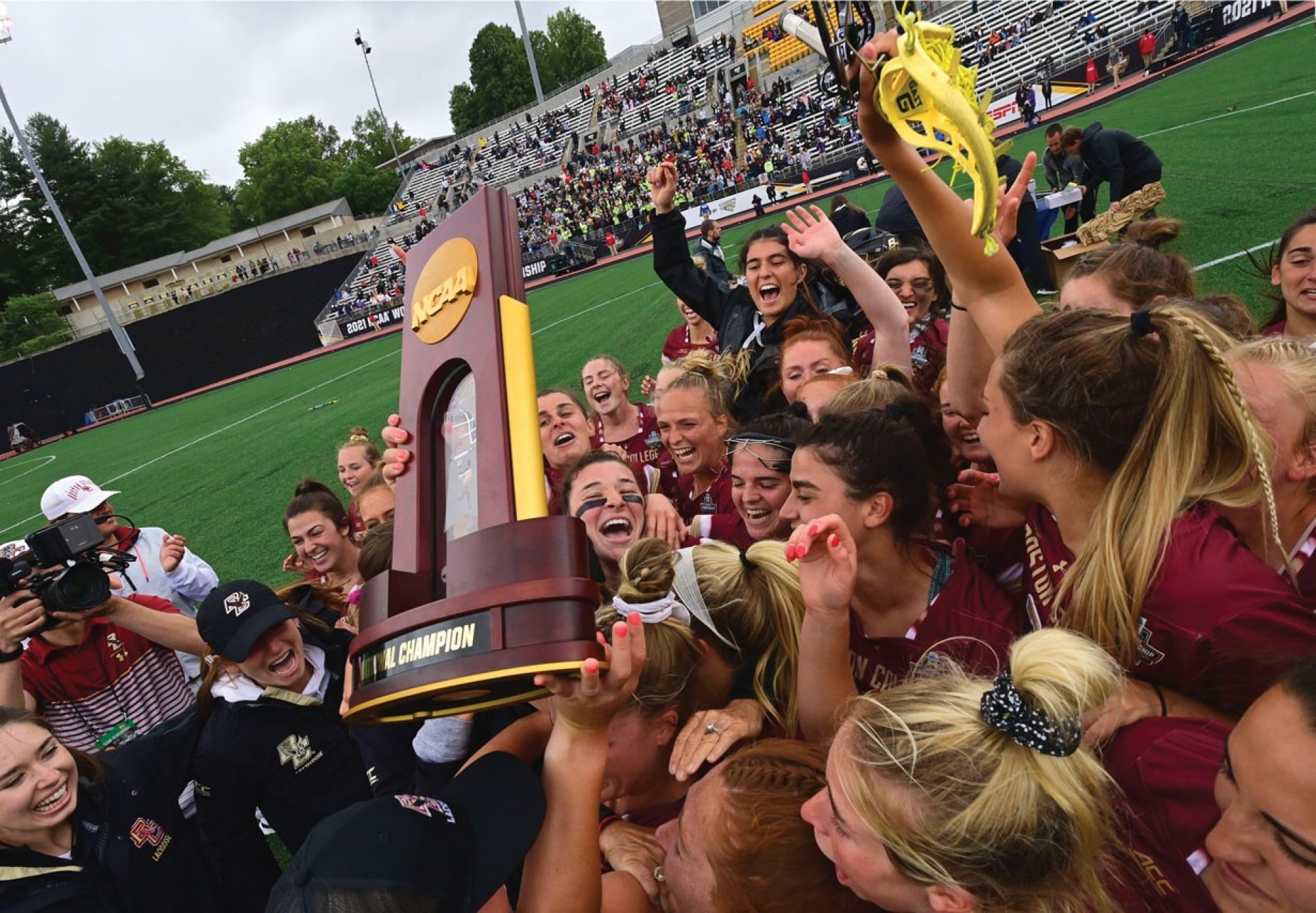 The women's lacrosse team hoisting the trophy in celebration