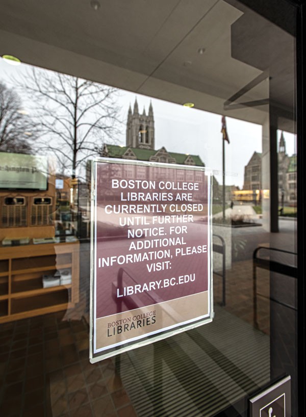 A closure sign on O'Neill Library with Gasson Hall reflected in the glass