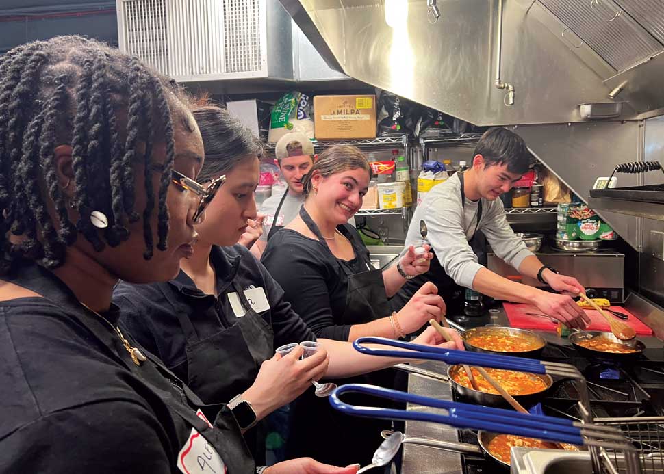 Group photo of students cooking over a stove.