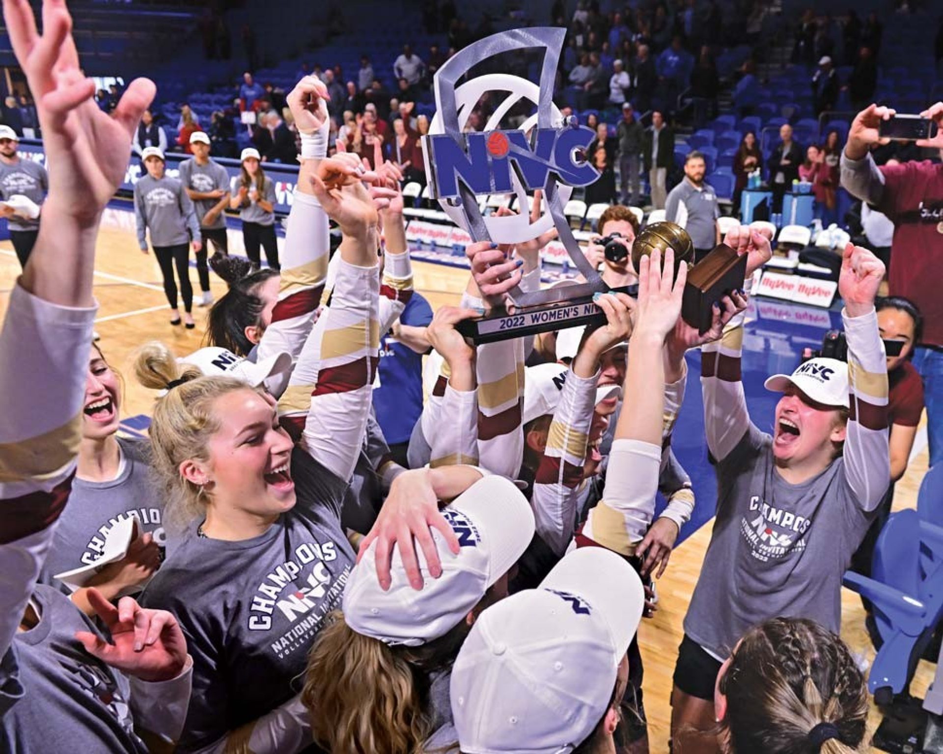 The women's volleyball team hoisting the trophy in celebration