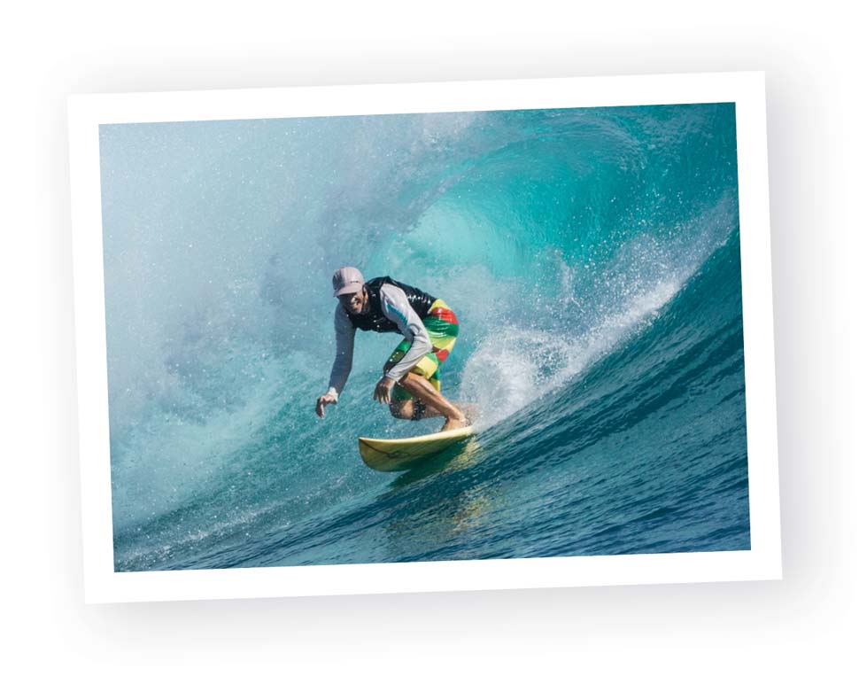 Greg surfing with wave curling in background.