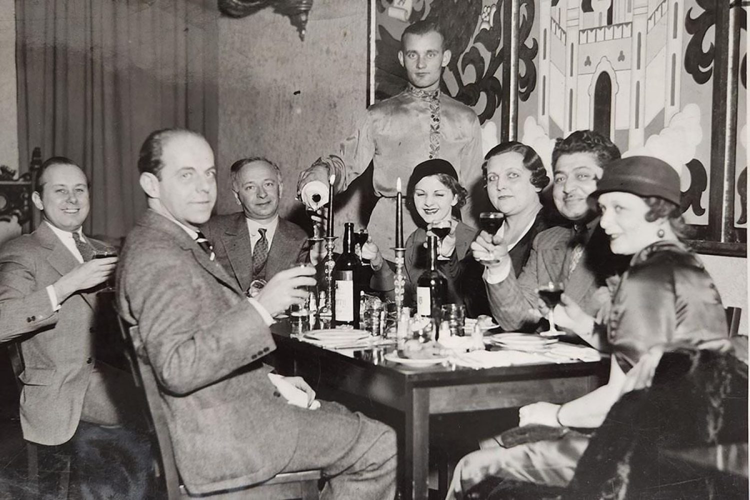 A historical photo showing a group of adults dining in a restaurant