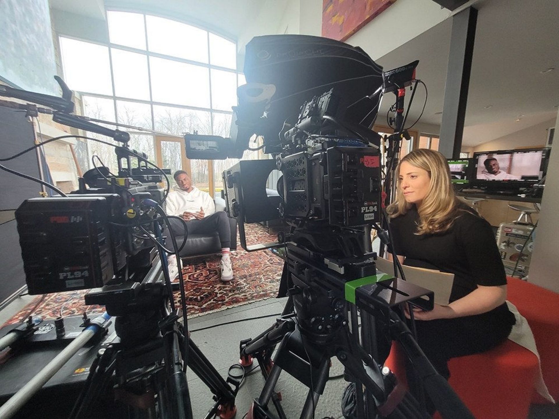 Kristen Lappas in the director's chair with Giannis sitting in the background