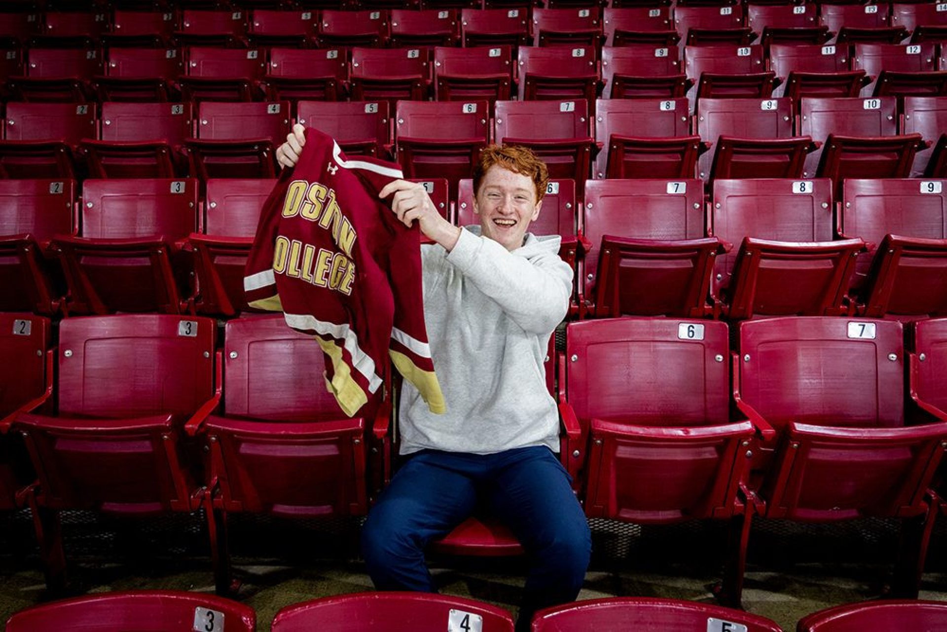 Danny Gillis waving his hockey jersey sitting in the stands