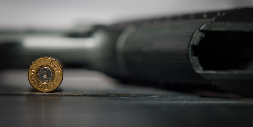Photo of A bullet lying next to the grip of a black handgun