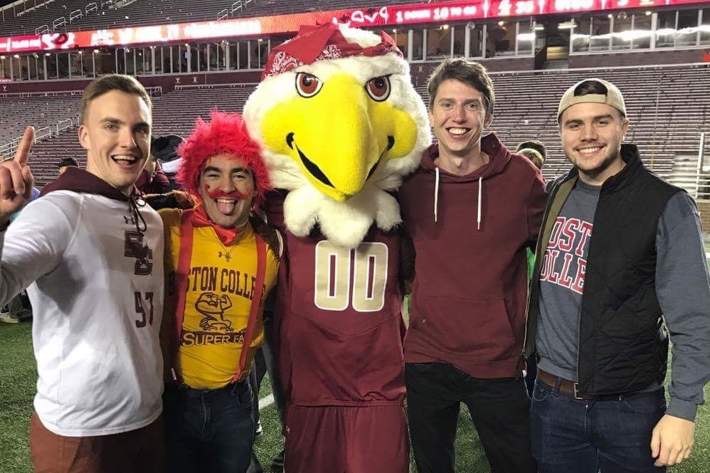 students smile with Baldwin on football field