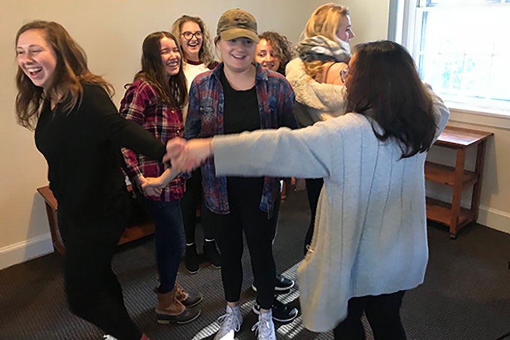 students hold hands in circle smiling