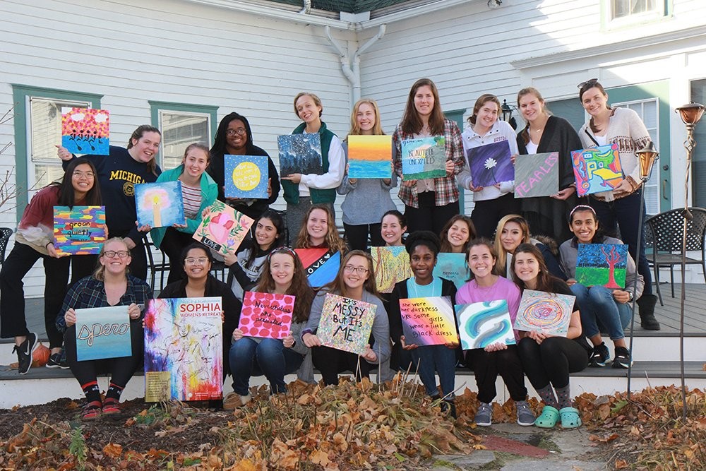 group of women holding art canvases