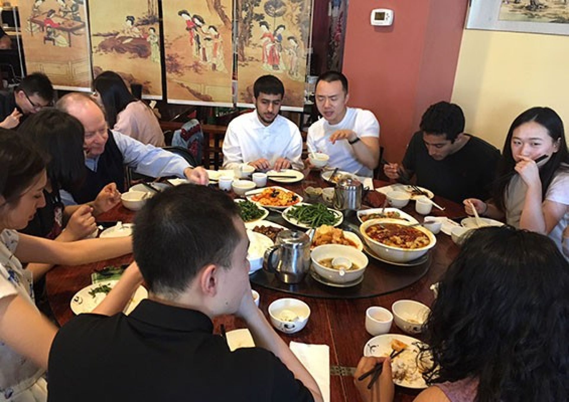 students and professor sit at circular table eating