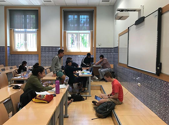 students sit in room studying on computers and in groups
