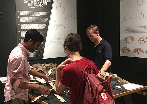 students gather around table building with wooden pieces