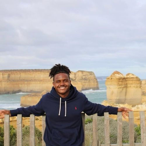 student standing in front a collection of limestone stacks off the shore of Port Campbell National Park by the Great Ocean Road in Victoria, Australia.
