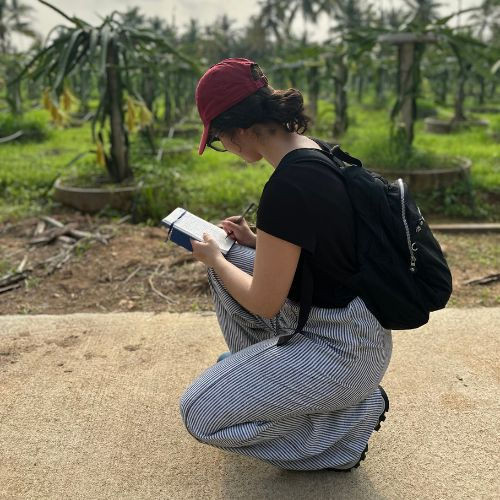 Student crouching in front of dense forestry 
