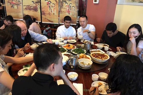 students and professor sit at circular table eating