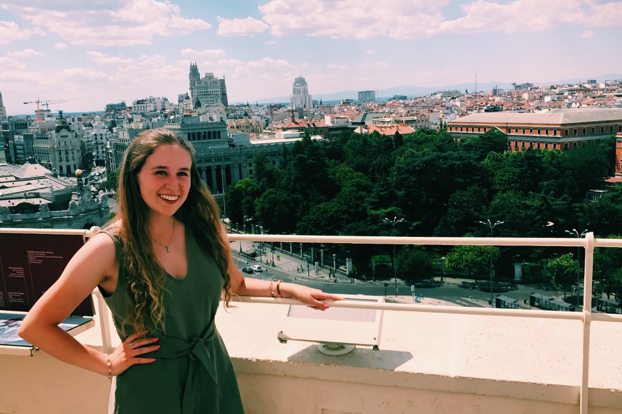 woman in green dress posing in front of city backdrop