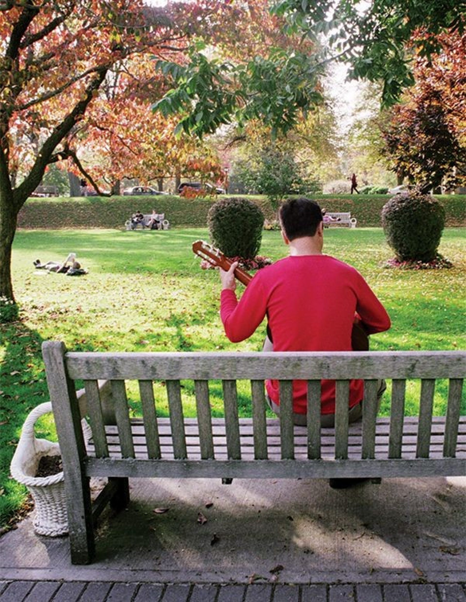 A person playing guitar sitting on a bench