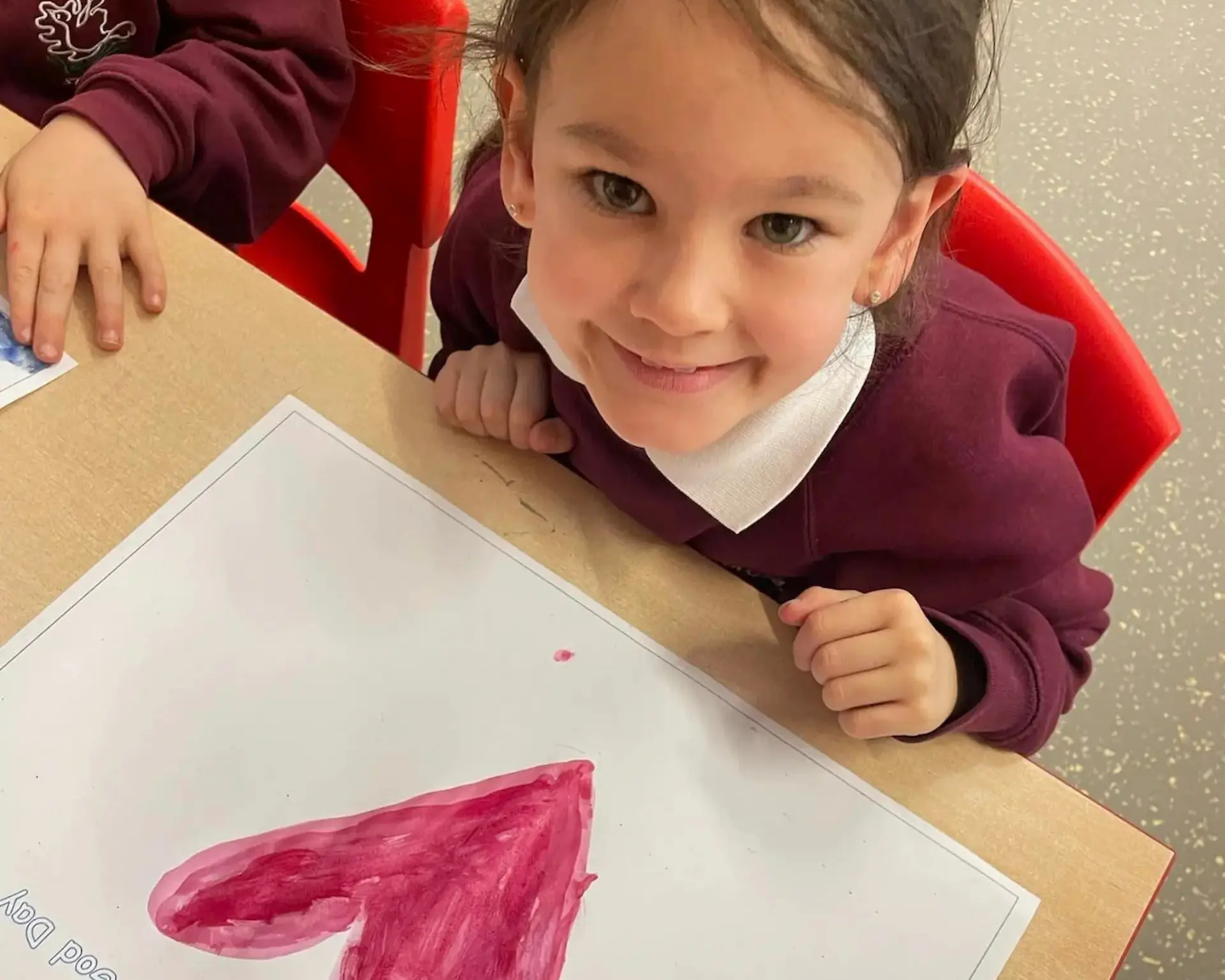 Girl smiles with drawing of heart.