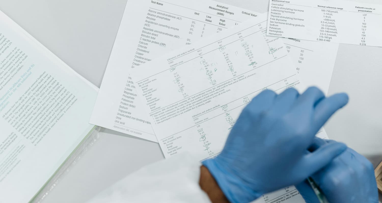 Stock photo of hands in latex gloves over research papers