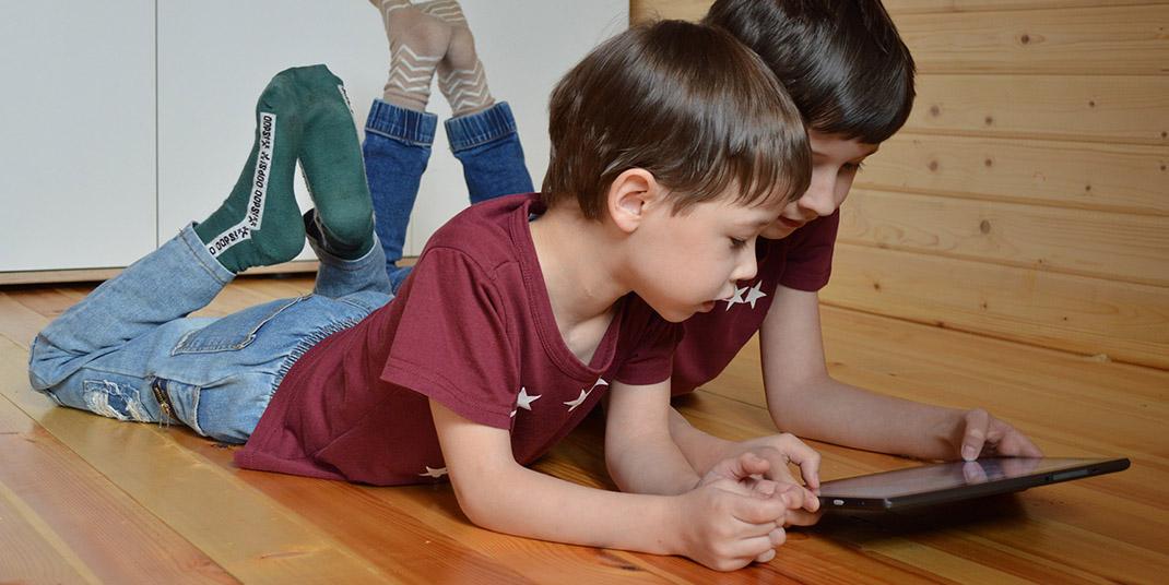 Two young kids looking at a tablet