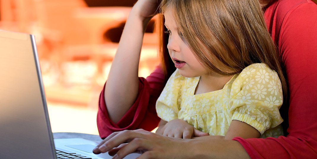 A child and adult using a laptop