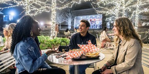Three students eating outside at night